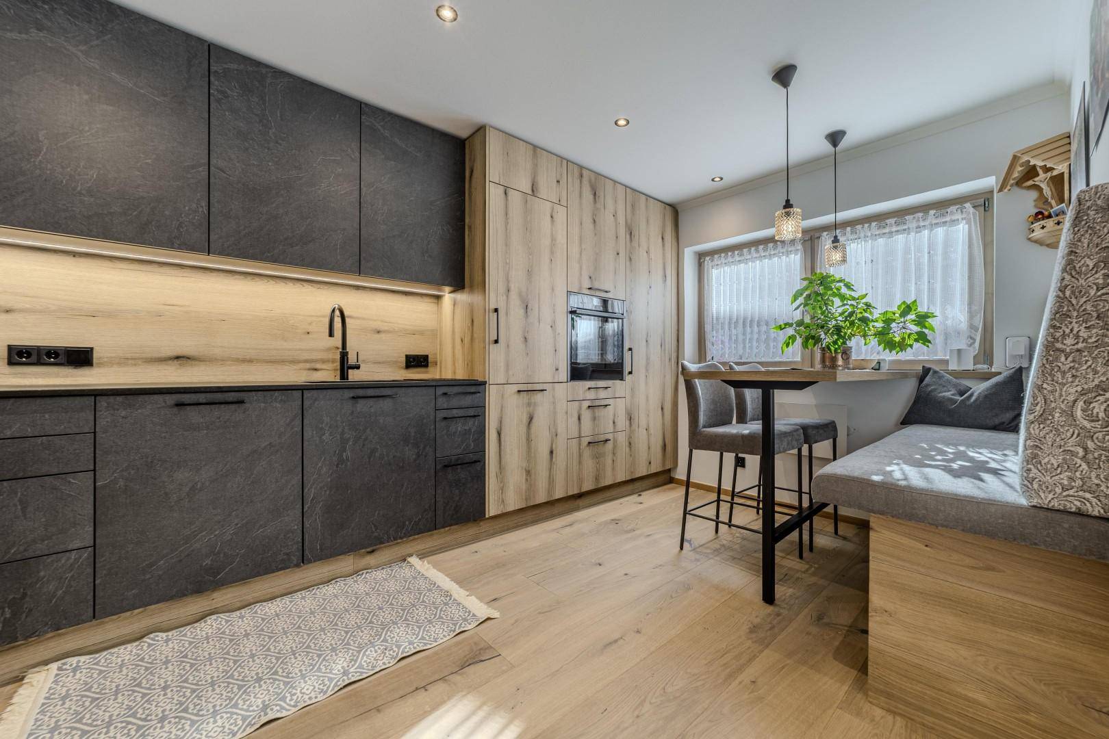 Stilvolle Küche mit Holzboden, Sitzbank und modernen Geräten.