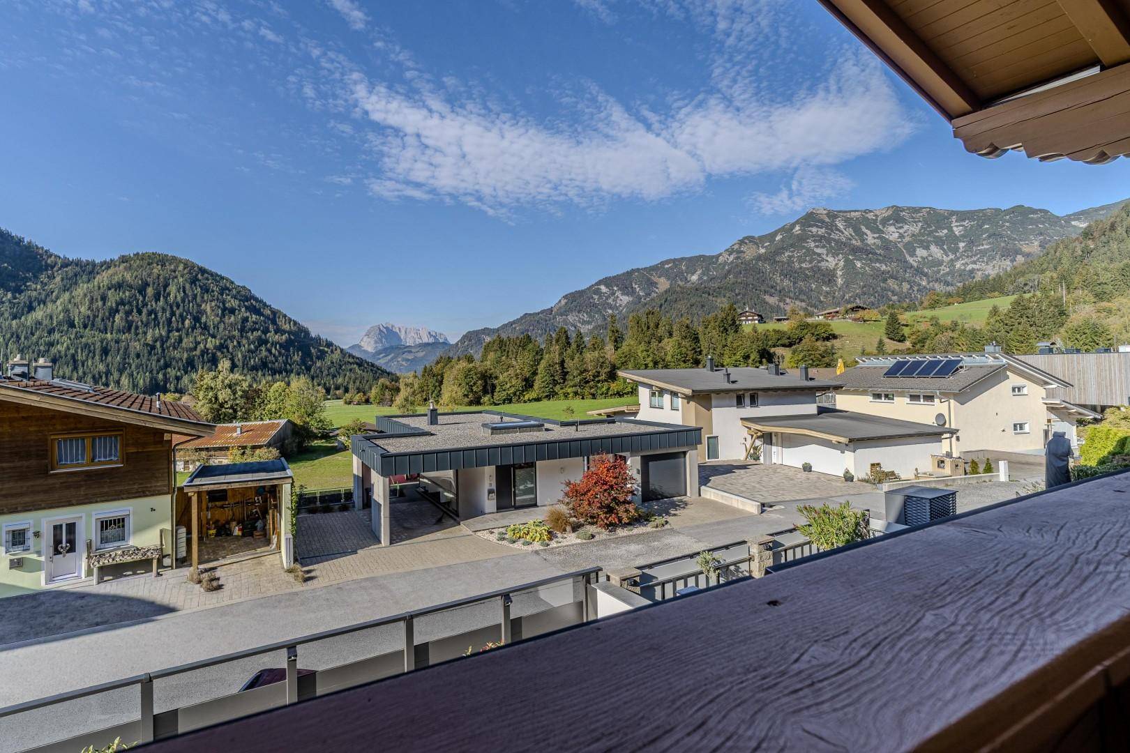 Weitläufiger Blick vom Balkon auf die umliegende Berglandschaft und benachbarte Häuser.
