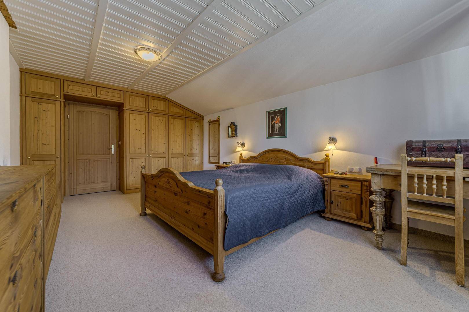 Geräumiges Schlafzimmer mit Holzbett, Einbauschränken und Teppichboden.