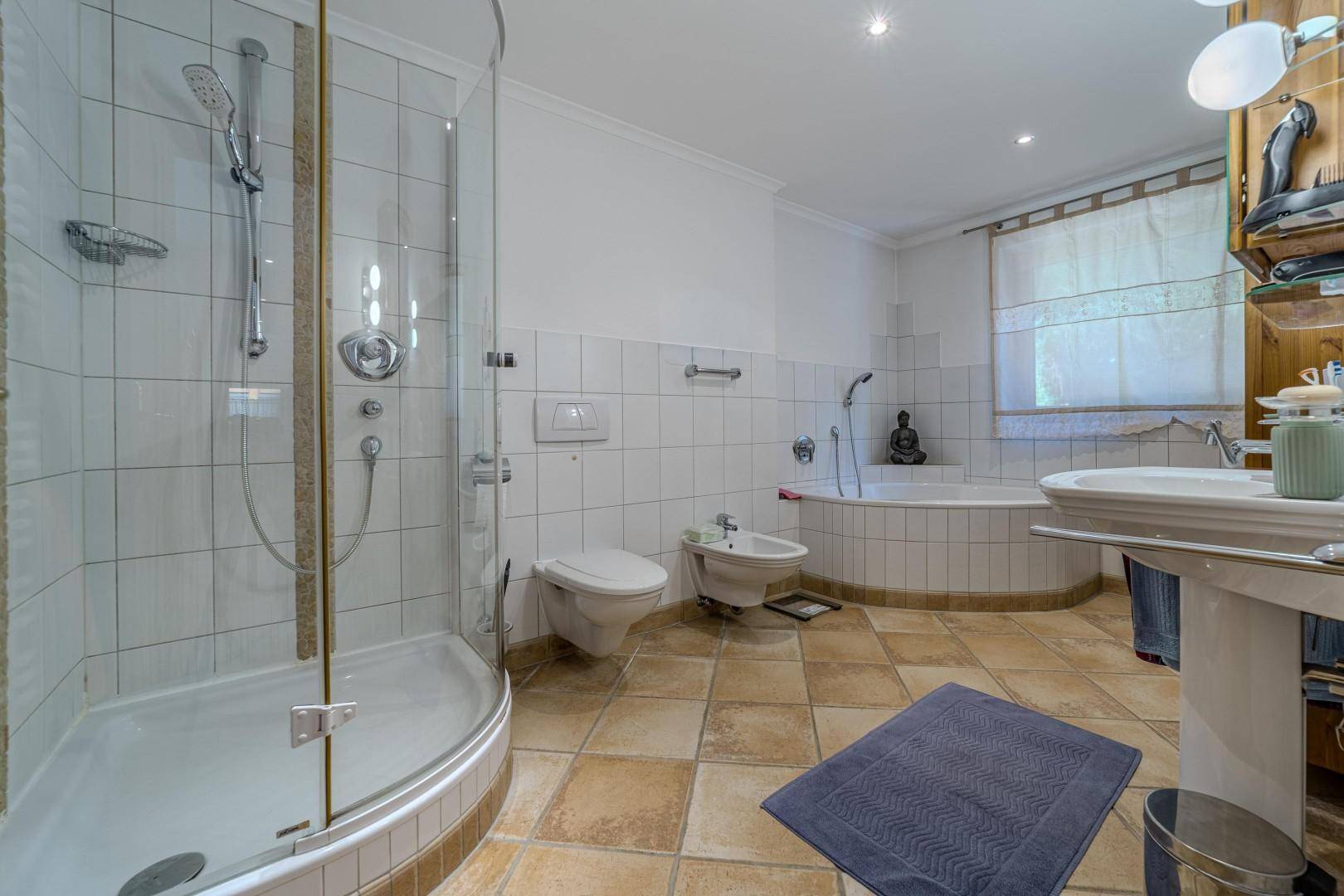Großes Badezimmer mit Dusche, Eckbadewanne, Bidet und Fliesenboden.
