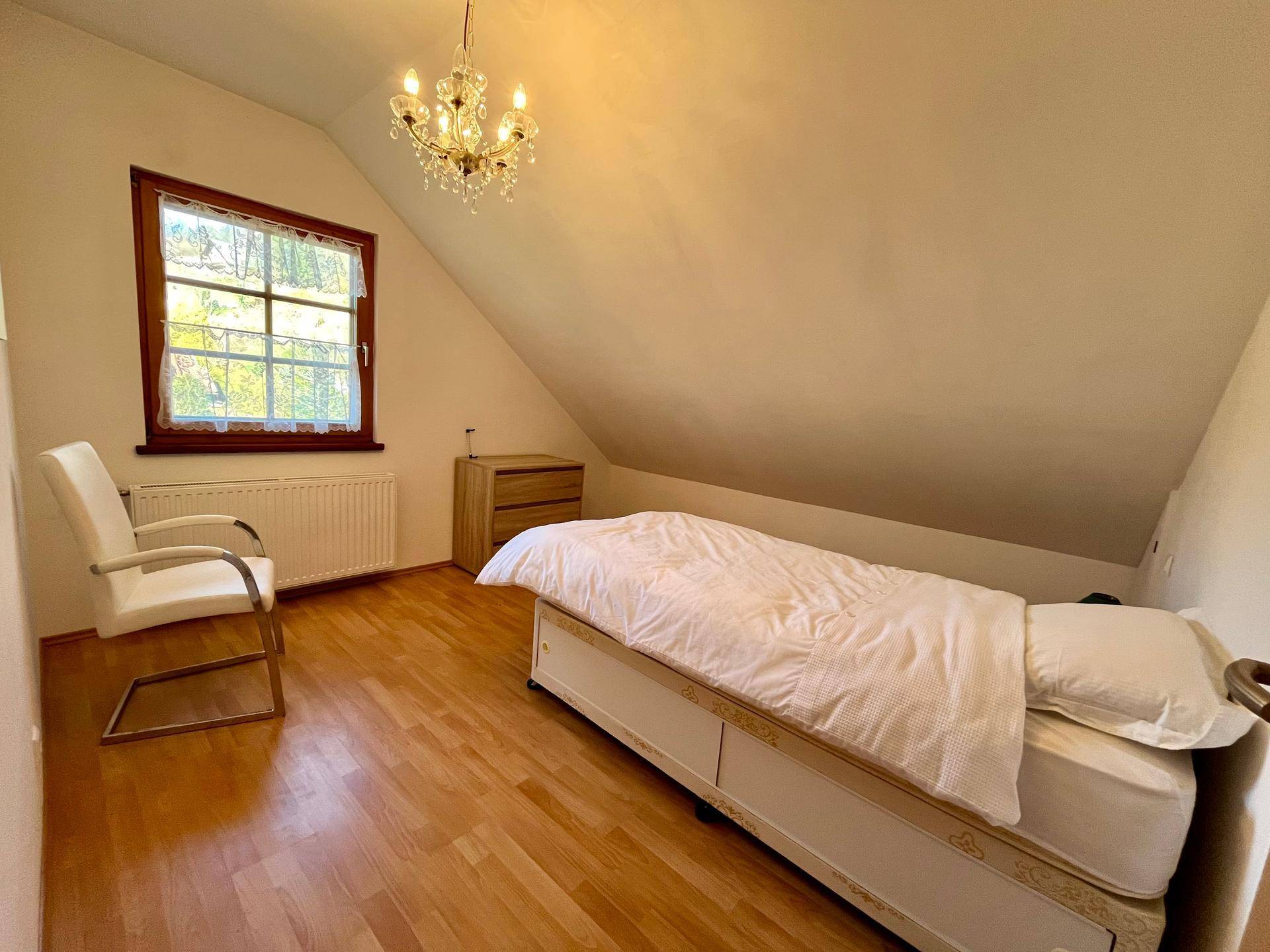 Gemütliches Schlafzimmer im Dachgeschoss mit Einzelbett, Laminatboden und Dachschräge.