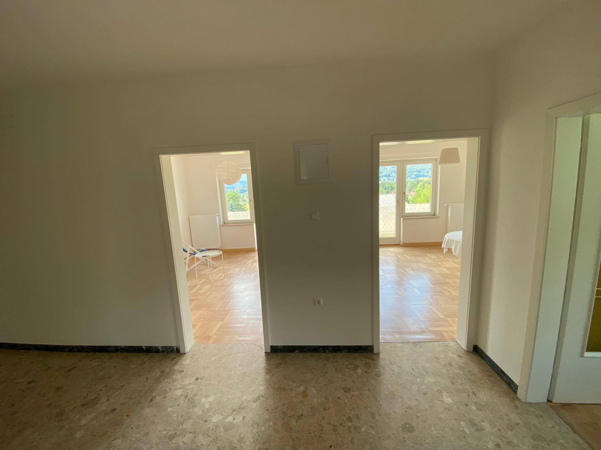 Heller Flurbereich mit Fliesenboden, der zu mehreren Zimmern mit Parkettboden führt.