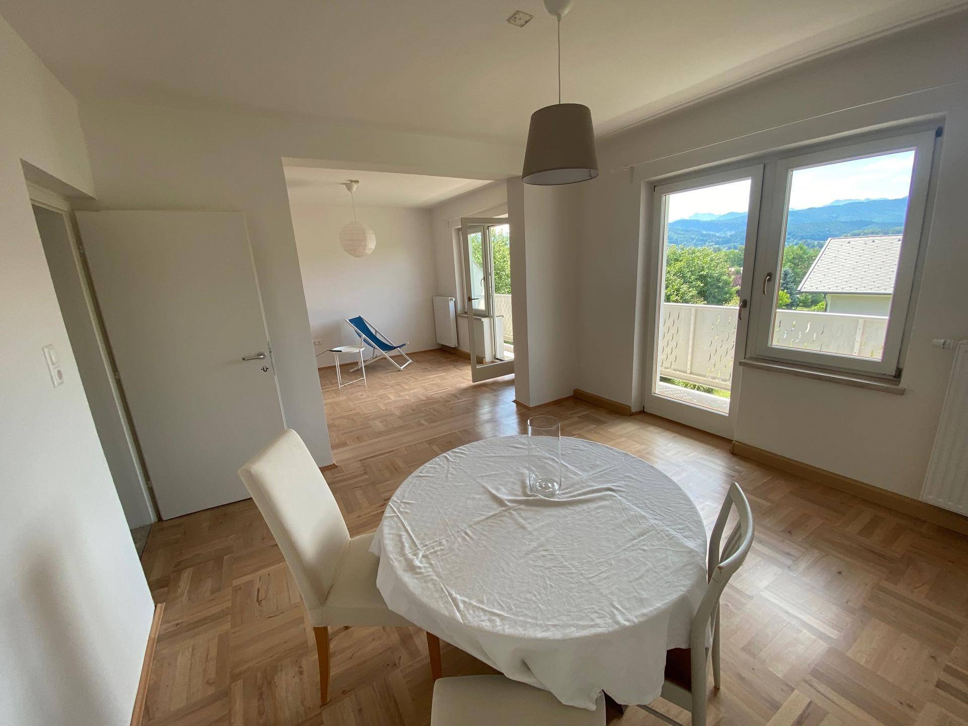 Heller Wohn- und Essbereich mit Parkettboden, Esstisch und Zugang zu einem Balkon mit Weitblick.