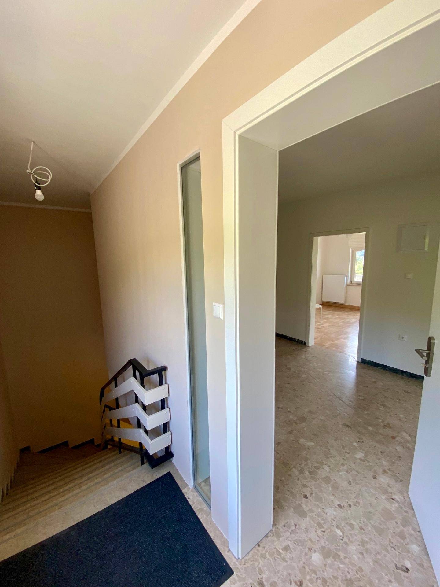 Heller Eingangsbereich mit Treppe und Fliesenboden, der zu den oberen Etagen führt.