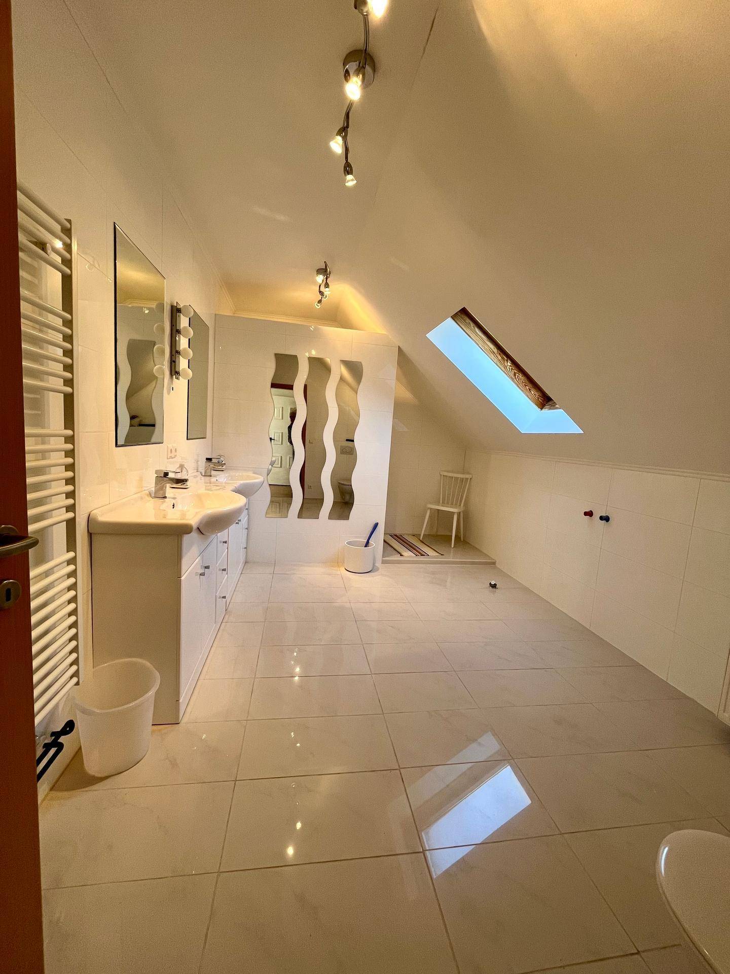 Modernes Badezimmer im Dachgeschoss mit Doppelwaschbecken, Fliesenboden und Dachfenster.
