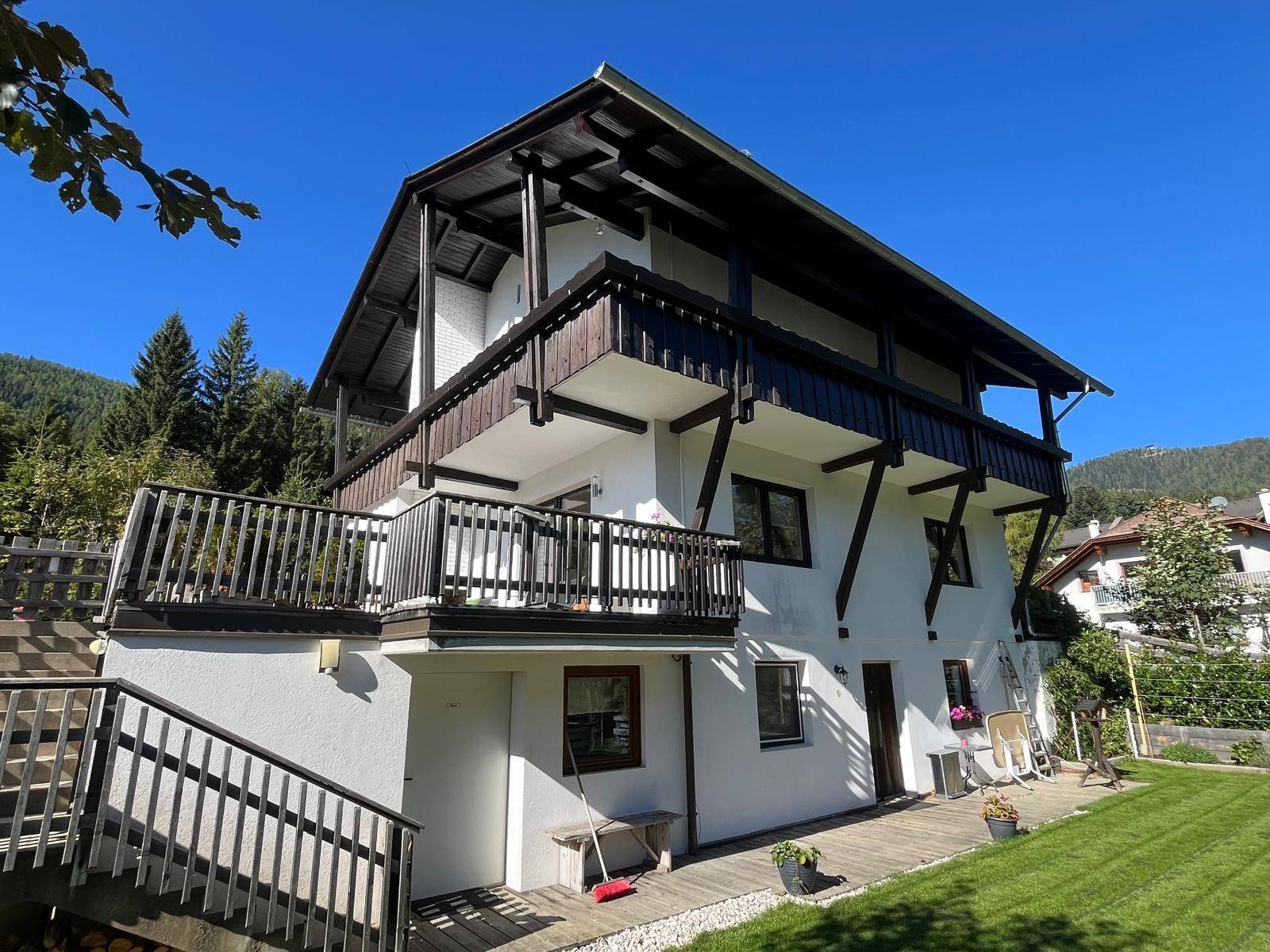 Ansicht des Hauses von der Seite mit mehreren Balkonen und einem gepflegten Rasenbereich.