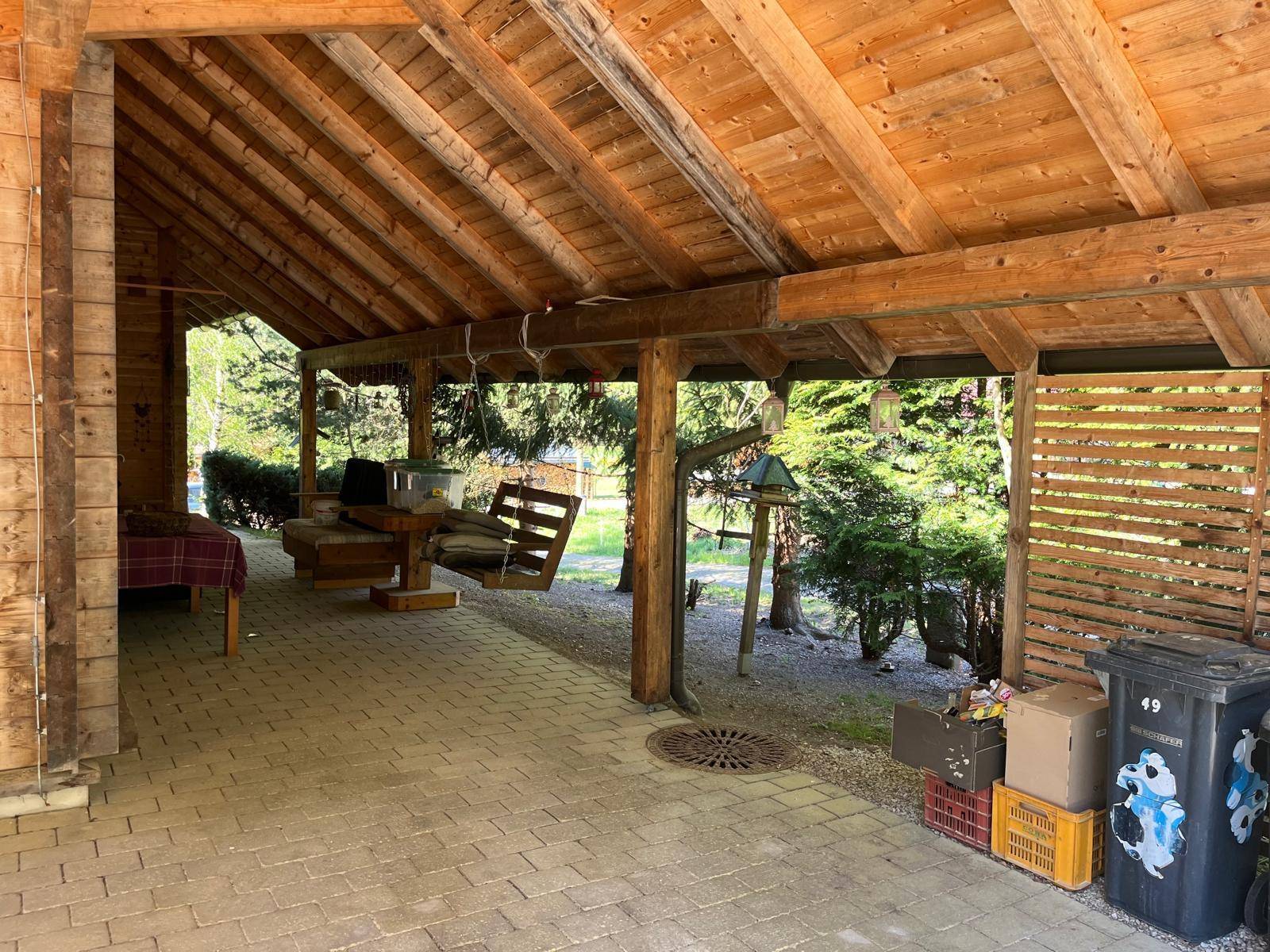 Geräumiger Carport mit Holzdach, bietet Schutz für Fahrzeuge und Gartengeräte.