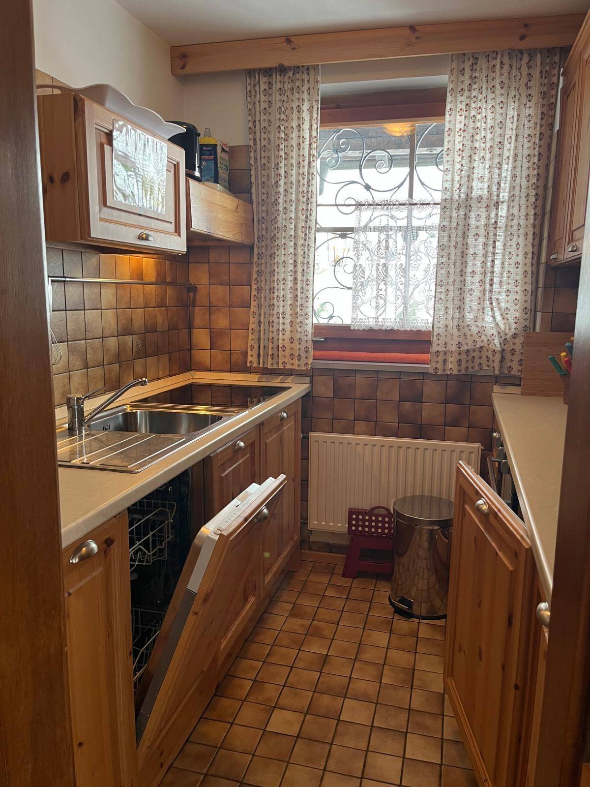 Kleine Küche im Landhausstil mit Holzschränken, Fliesenboden und Fenster.
