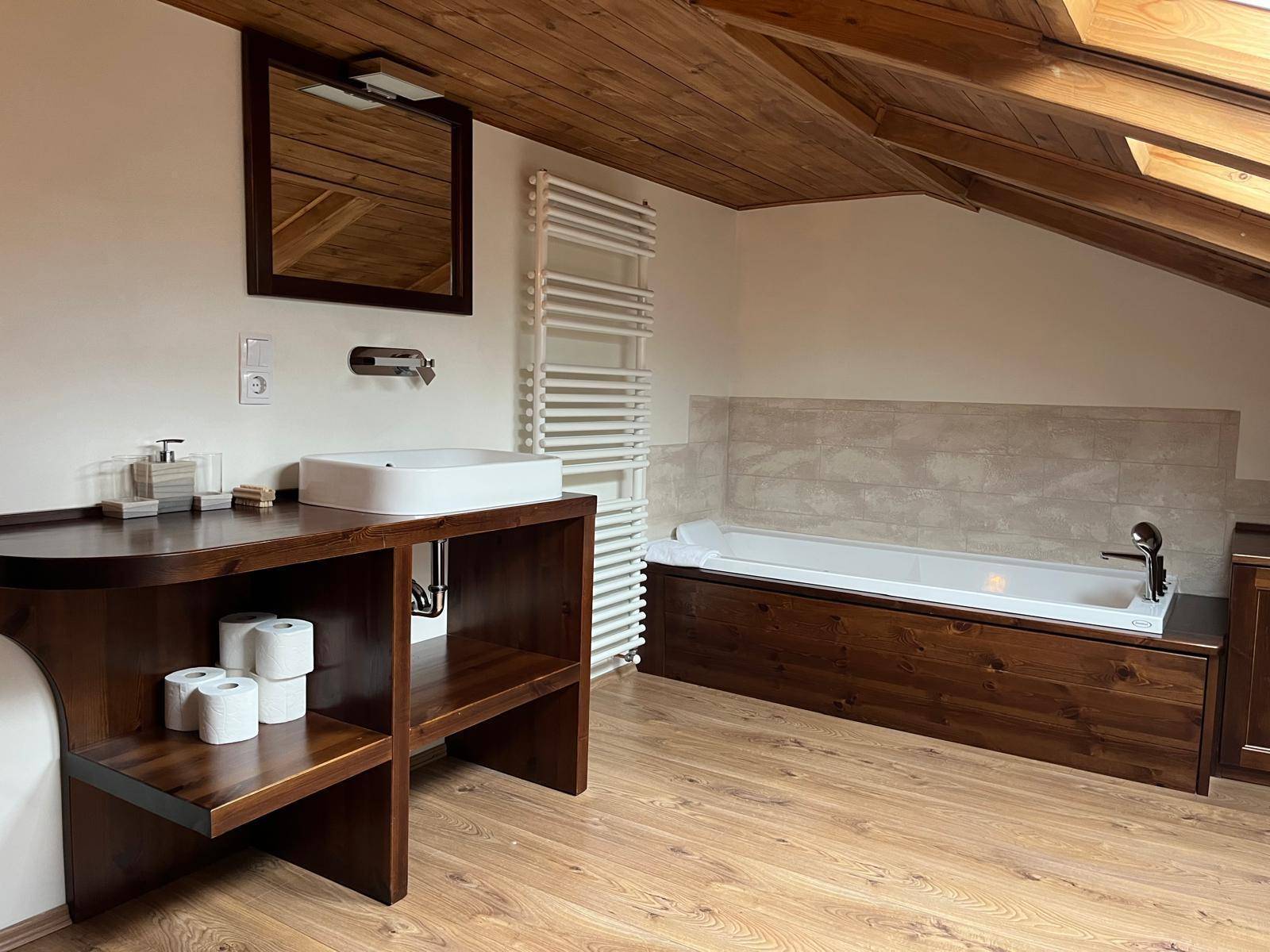 Geräumiges Badezimmer mit Badewanne, modernem Waschbecken und beheiztem Handtuchhalter.