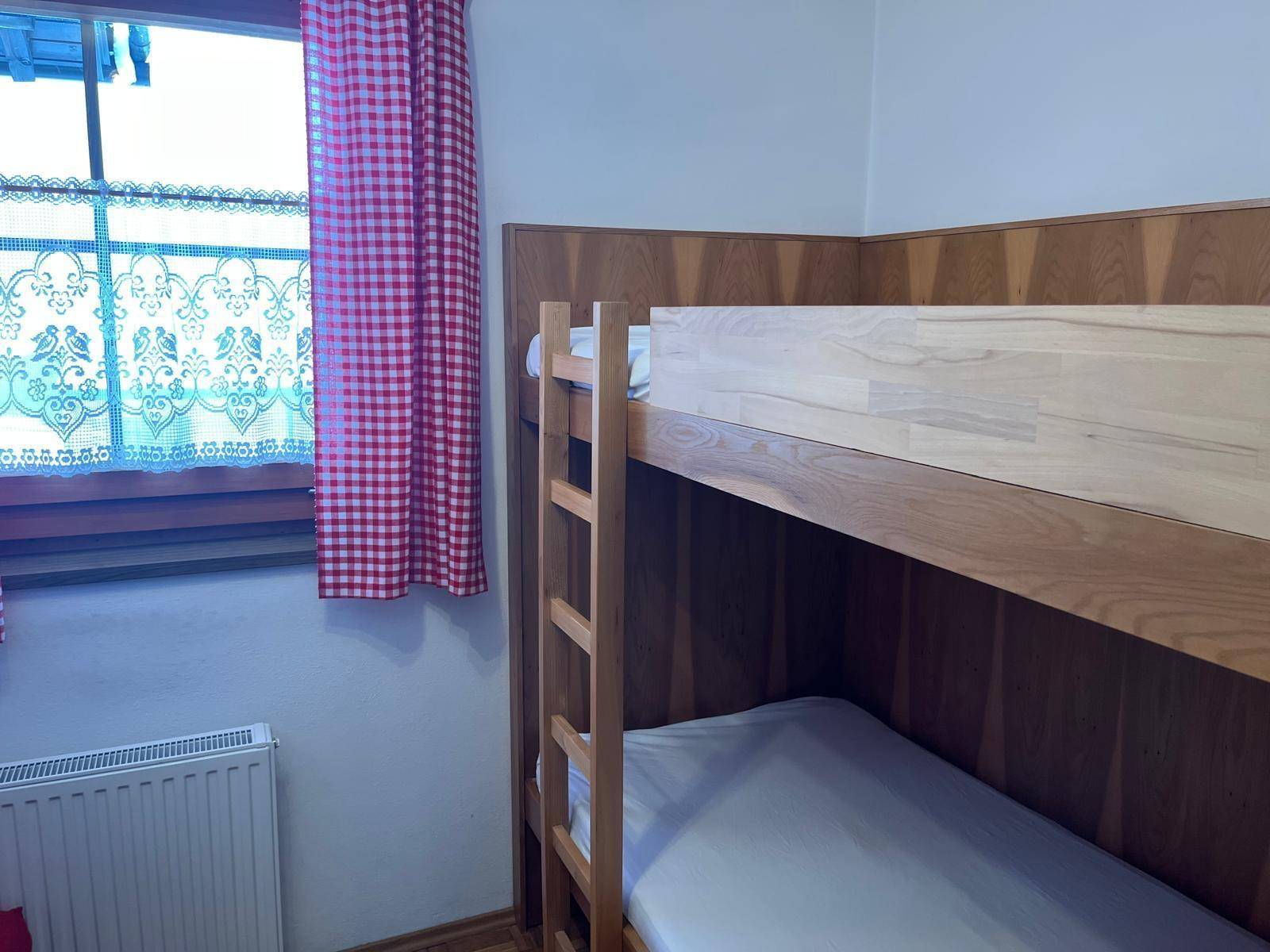Kinderzimmer mit Etagenbett und karierten Vorhängen im traditionellen Landhausstil.