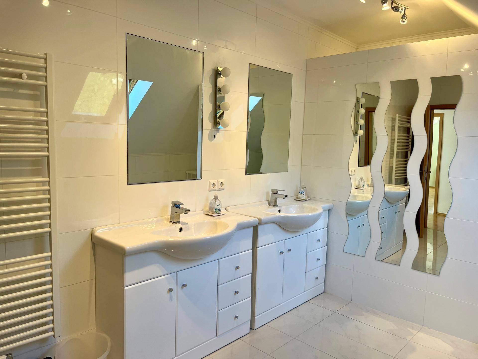 Helles Badezimmer im Dachgeschoss mit zwei Waschbecken und großen Spiegeln.