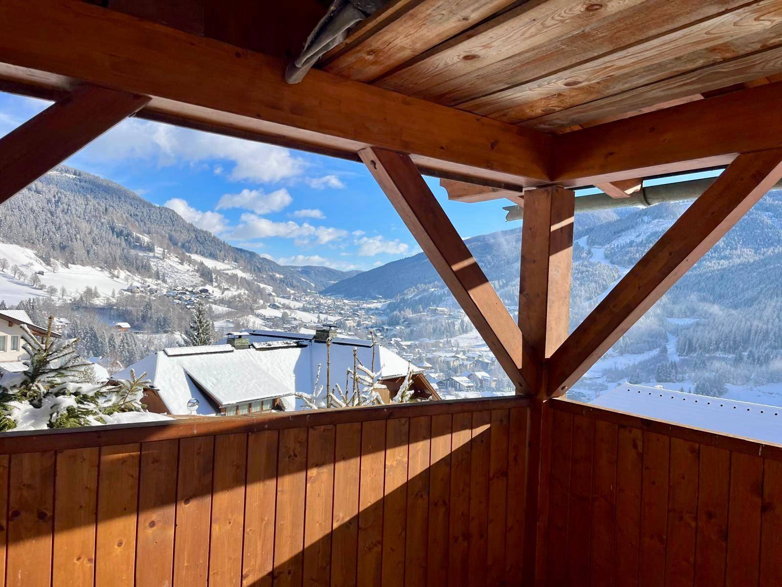 Überdachte Loggia aus Holz mit weitem Blick auf die umliegenden Berge und das Tal.