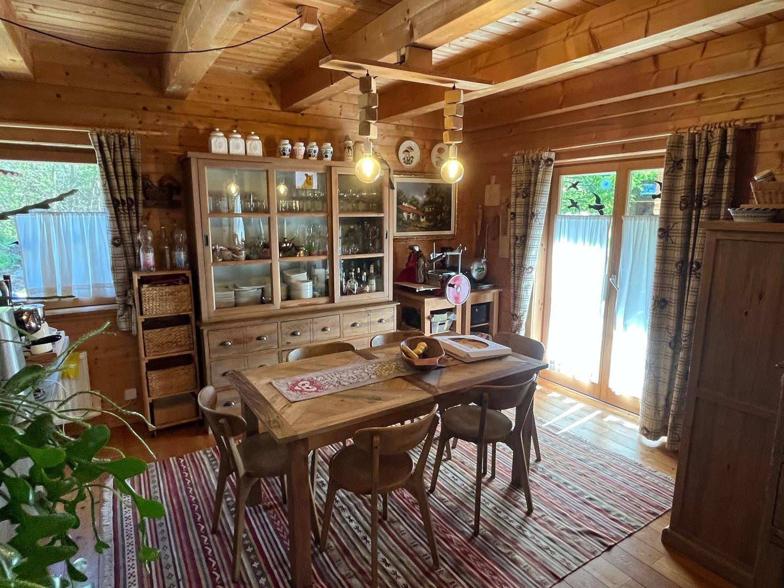 Rustikaler Essbereich mit Holztisch, Stühlen und großem Schrank, ideal für Familienessen.