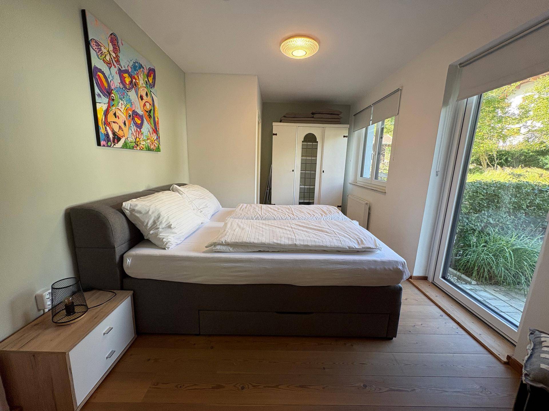 Schlafzimmer mit Doppelbett und direktem Zugang zu einem kleinen Außenbereich, hell und funktional.