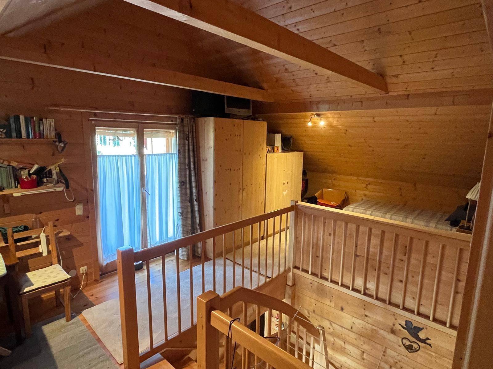 Offener Schlafbereich im Obergeschoss mit Holzgeländer und Blick auf den unteren Bereich.