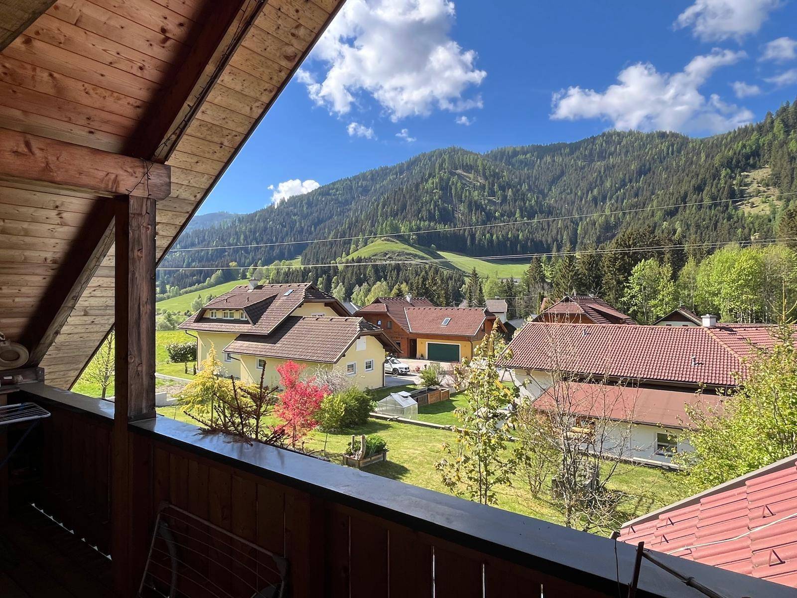 Sonniger Balkon mit weitem Blick über die grüne Landschaft und die umliegenden Berge.
