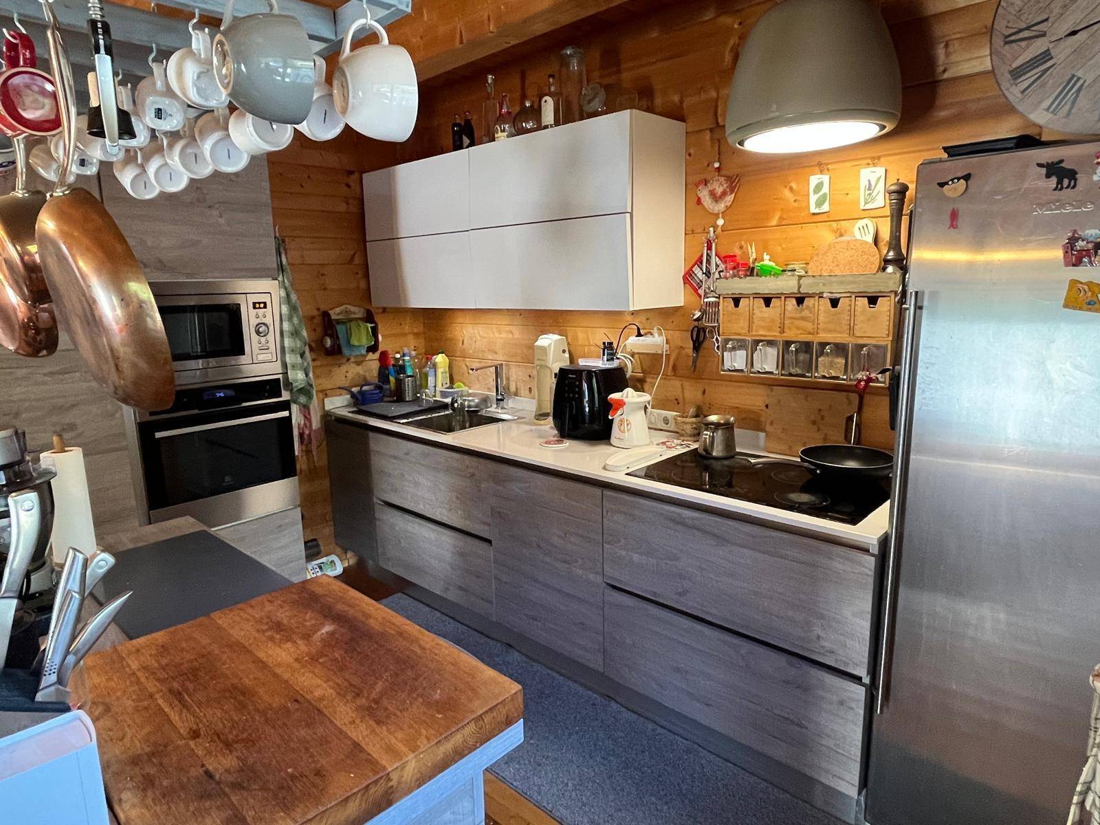 Moderne Einbauküche mit hellen Fronten und integrierten Geräten in rustikalem Ambiente.