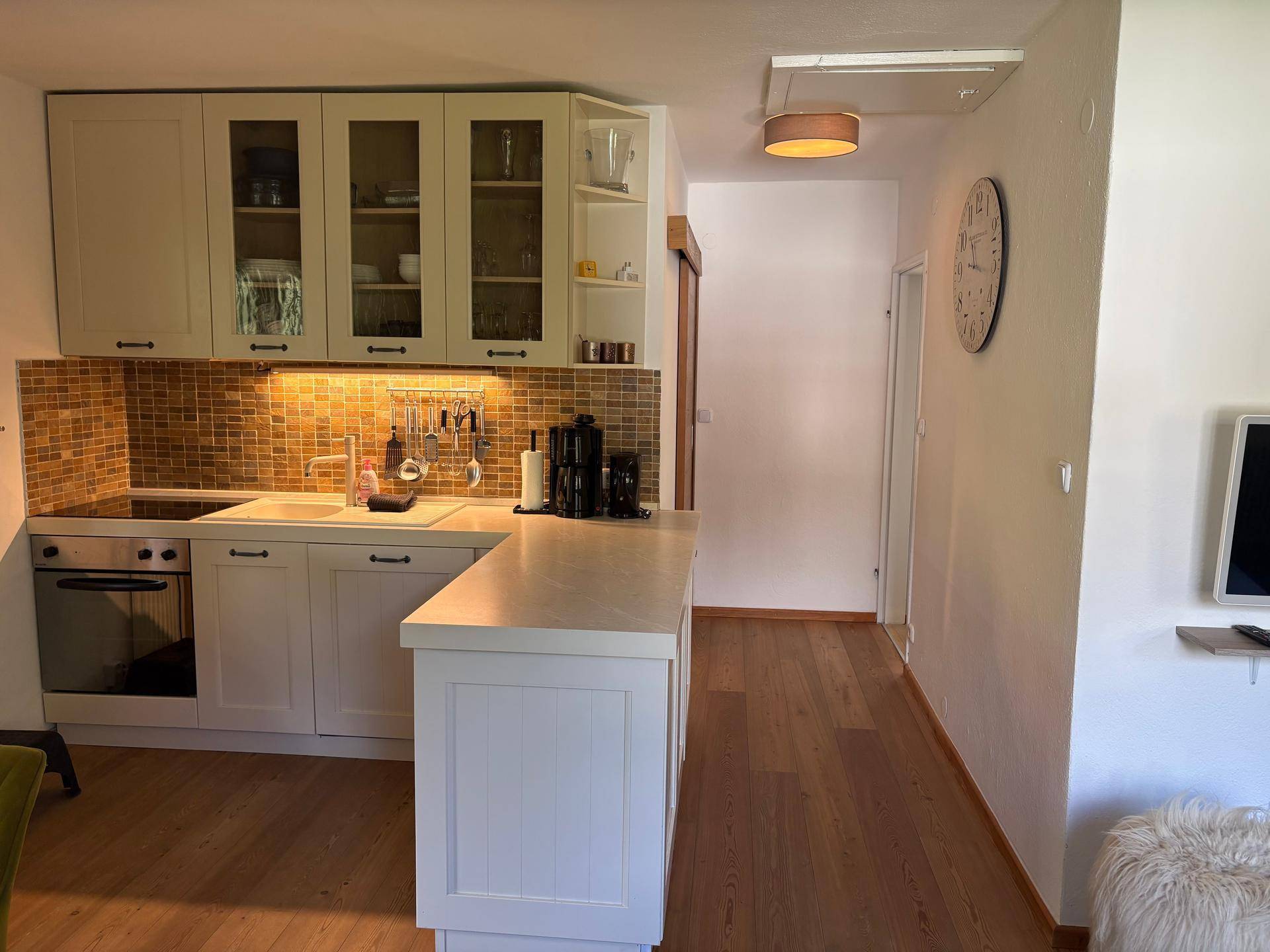 Helle Einbauküche mit weißen Schränken, Holztheke und modernen Geräten in offenem Design.