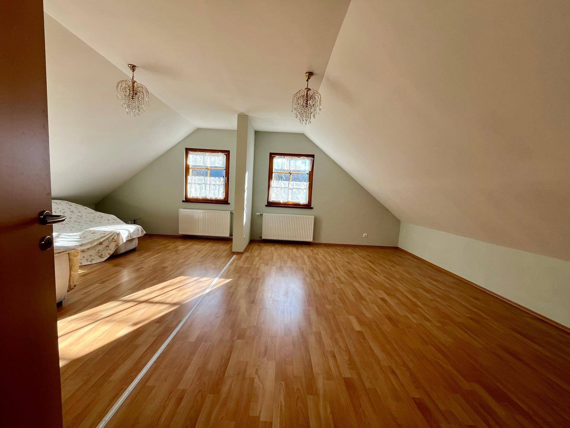 Geräumiger Dachbodenraum mit Laminatboden, Dachschrägen und zwei Fenstern.