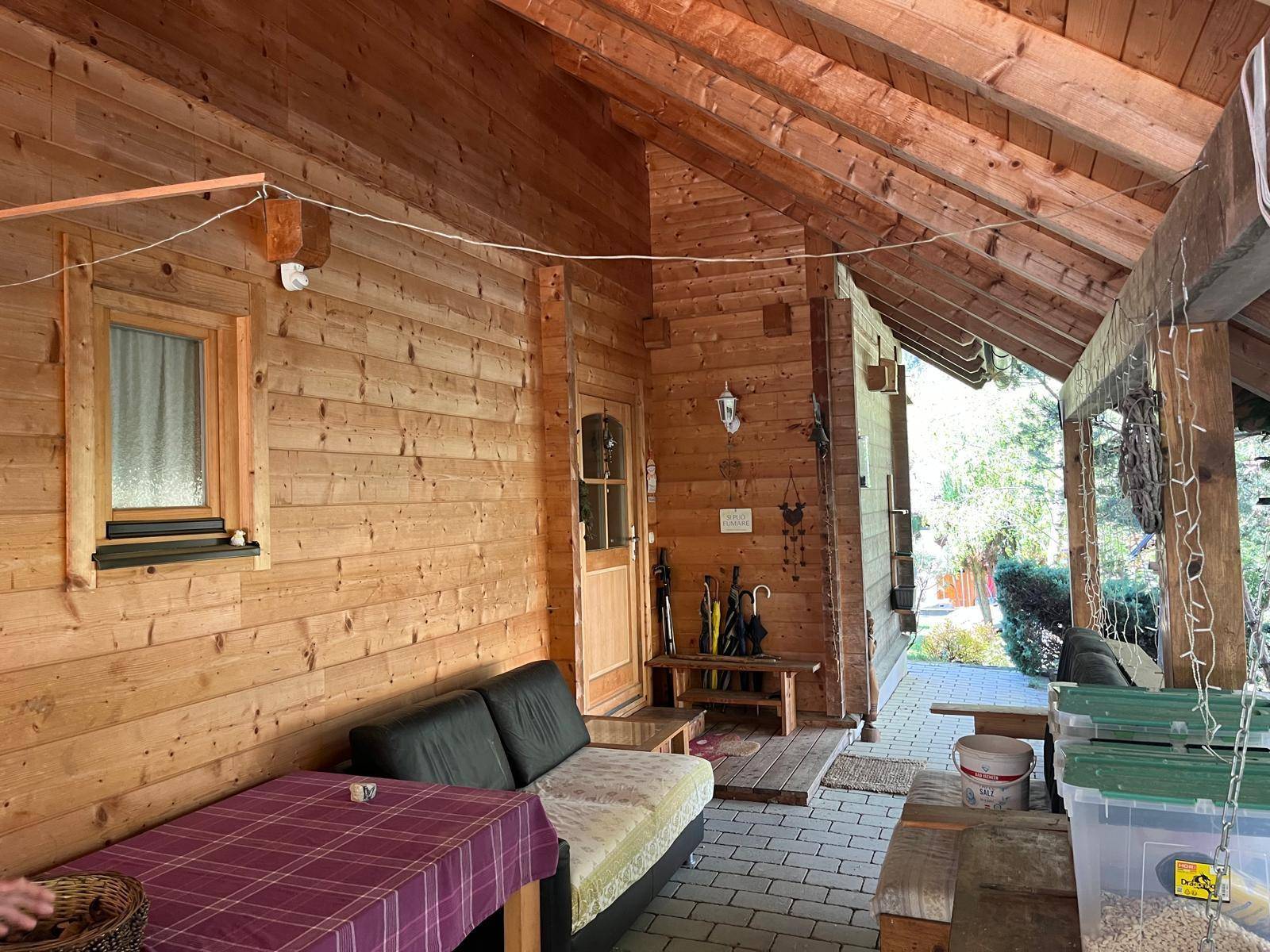 Überdachte Terrasse mit Sitzgelegenheiten und Zugang zum Haus, ideal für entspannte Stunden.