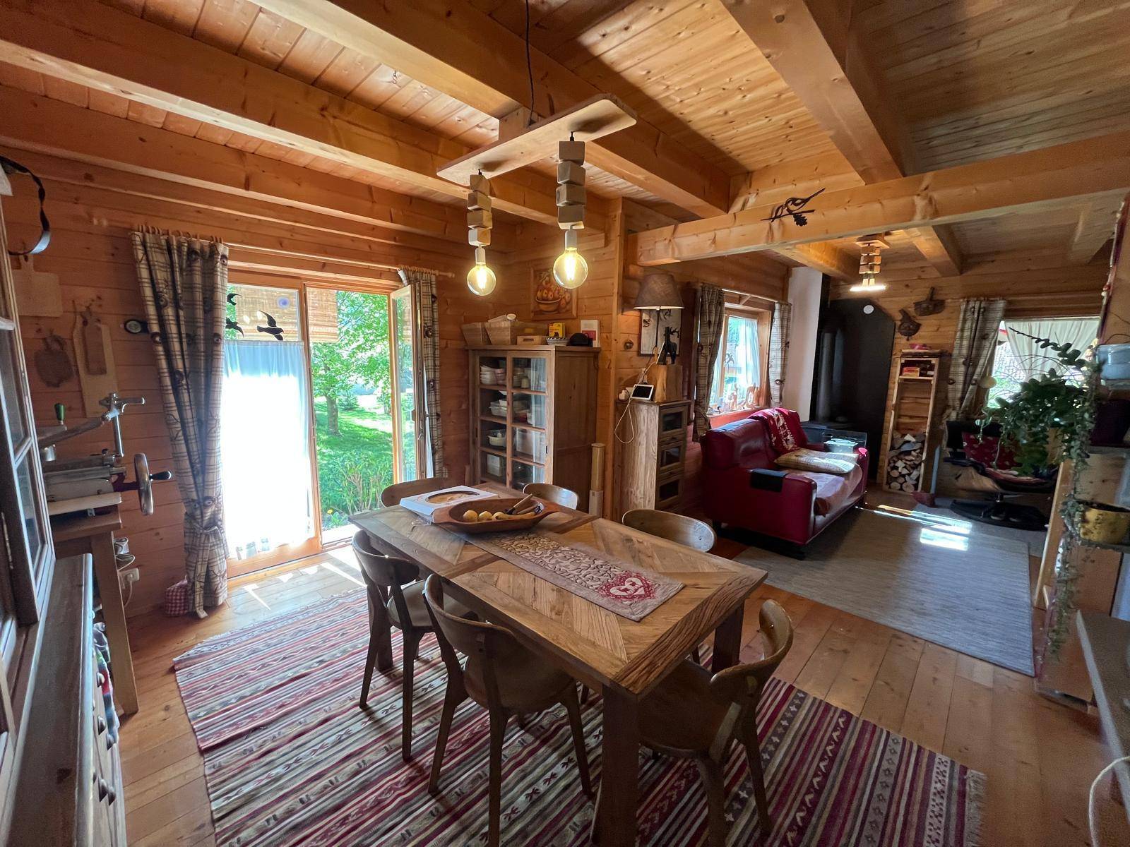 Rustikaler Essbereich mit Holztisch, Stühlen und Zugang zur Terrasse oder Garten.