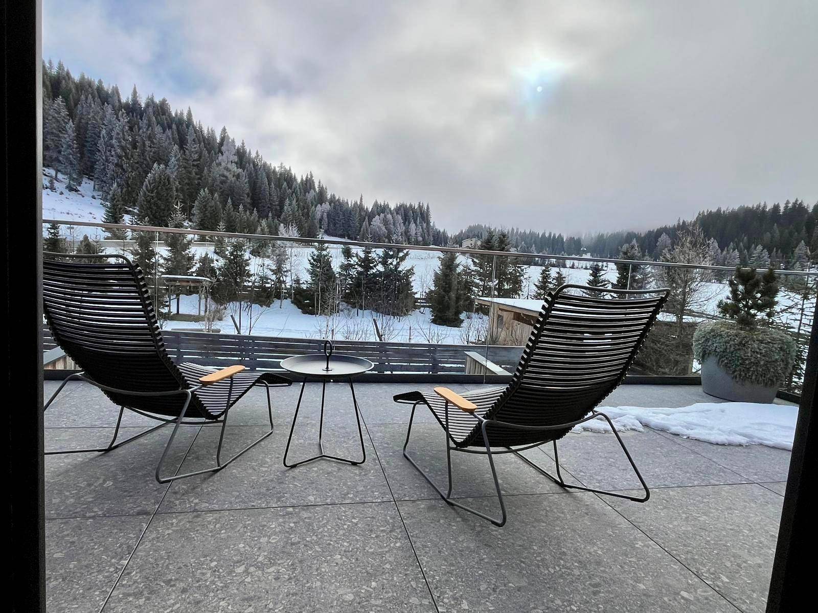 Gemütliche Terrasse mit Liegestühlen und einem atemberaubenden Blick auf die verschneite Berglandschaft.