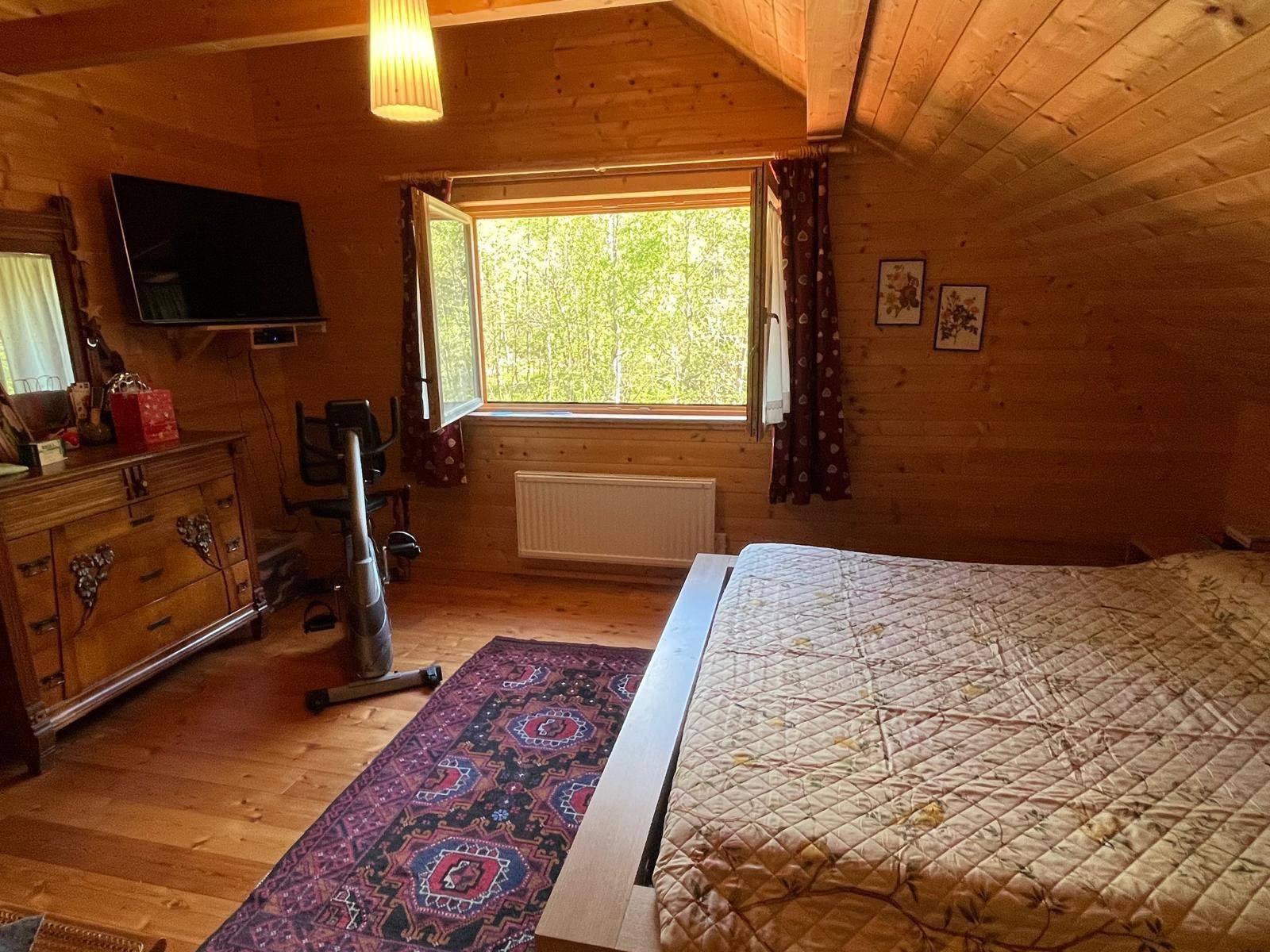 Geräumiges Schlafzimmer im Dachgeschoss mit Doppelbett, Holzmöbeln und Fenster.
