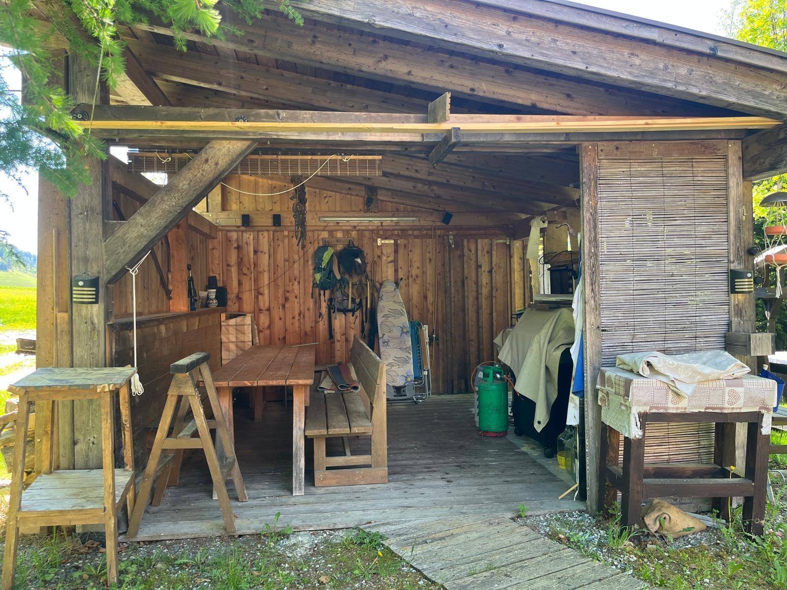 Rustikaler Gartenpavillon mit Holztisch und Bänken, ideal für gesellige Stunden im Freien.