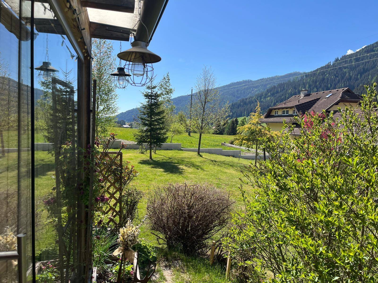 Weitläufiger Garten mit grüner Rasenfläche und Blick auf die umliegende Berglandschaft.