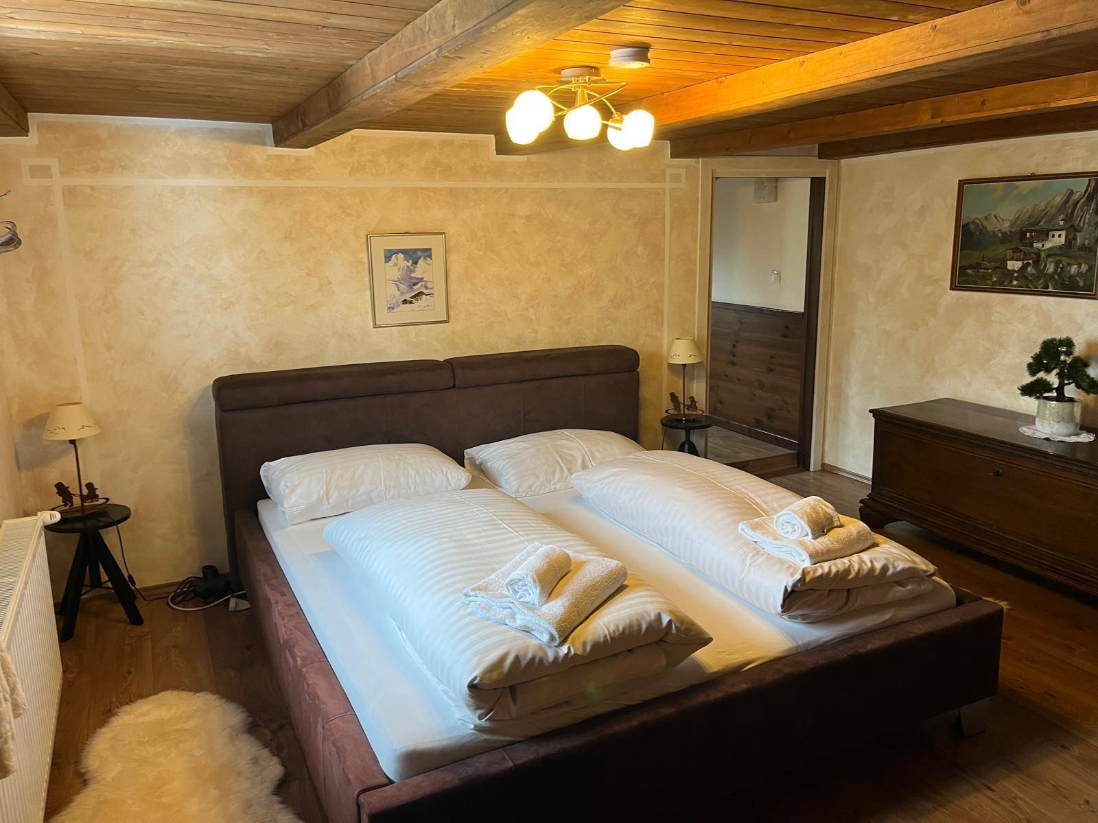 Schlafzimmer im Landhausstil mit Holzbalkendecke, Doppelbett und rustikalen Möbeln.