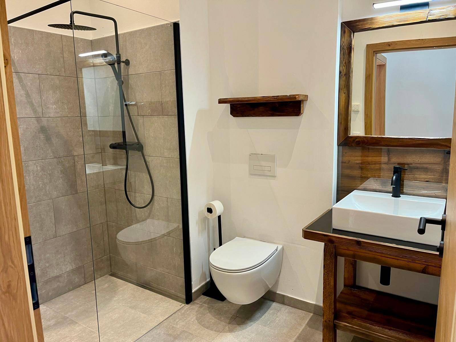 Modernes Badezimmer mit begehbarer Dusche, wandhängendem WC und stilvollem Holzwaschtisch.
