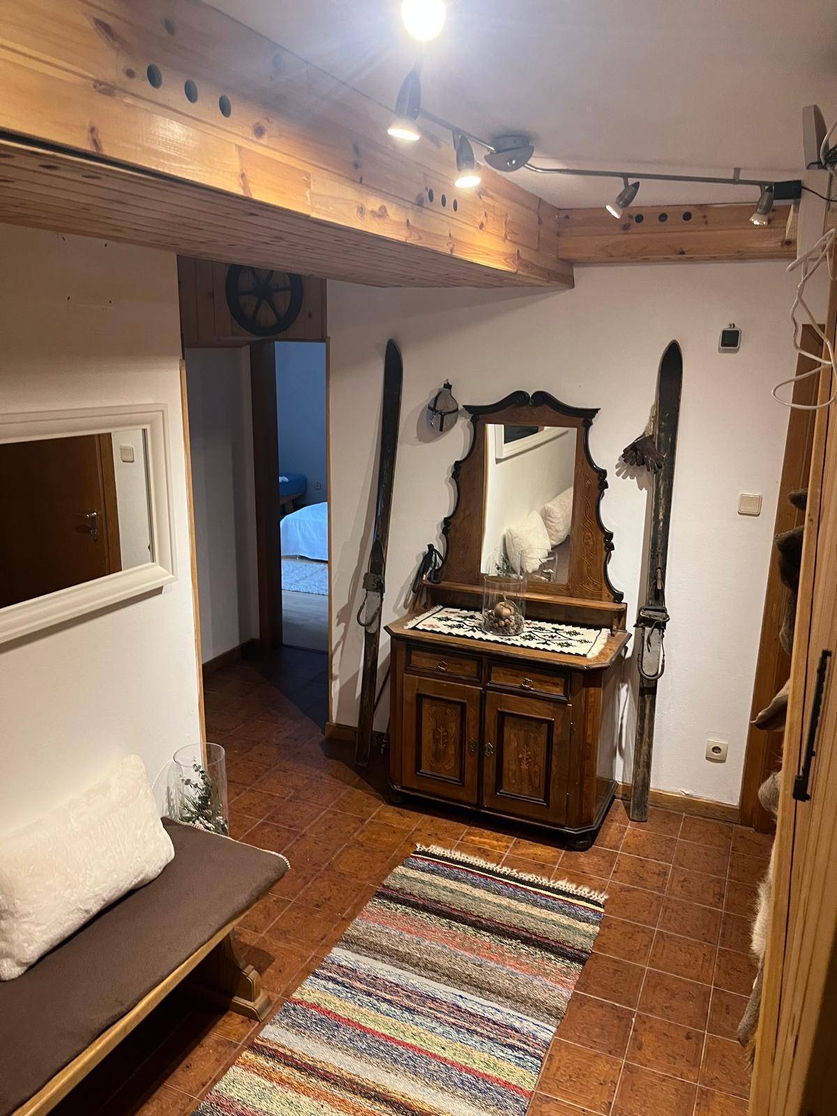 Rustikaler Flur mit Holzbalkendecke, Fliesenboden und traditionellen Möbeln und Dekorationen.