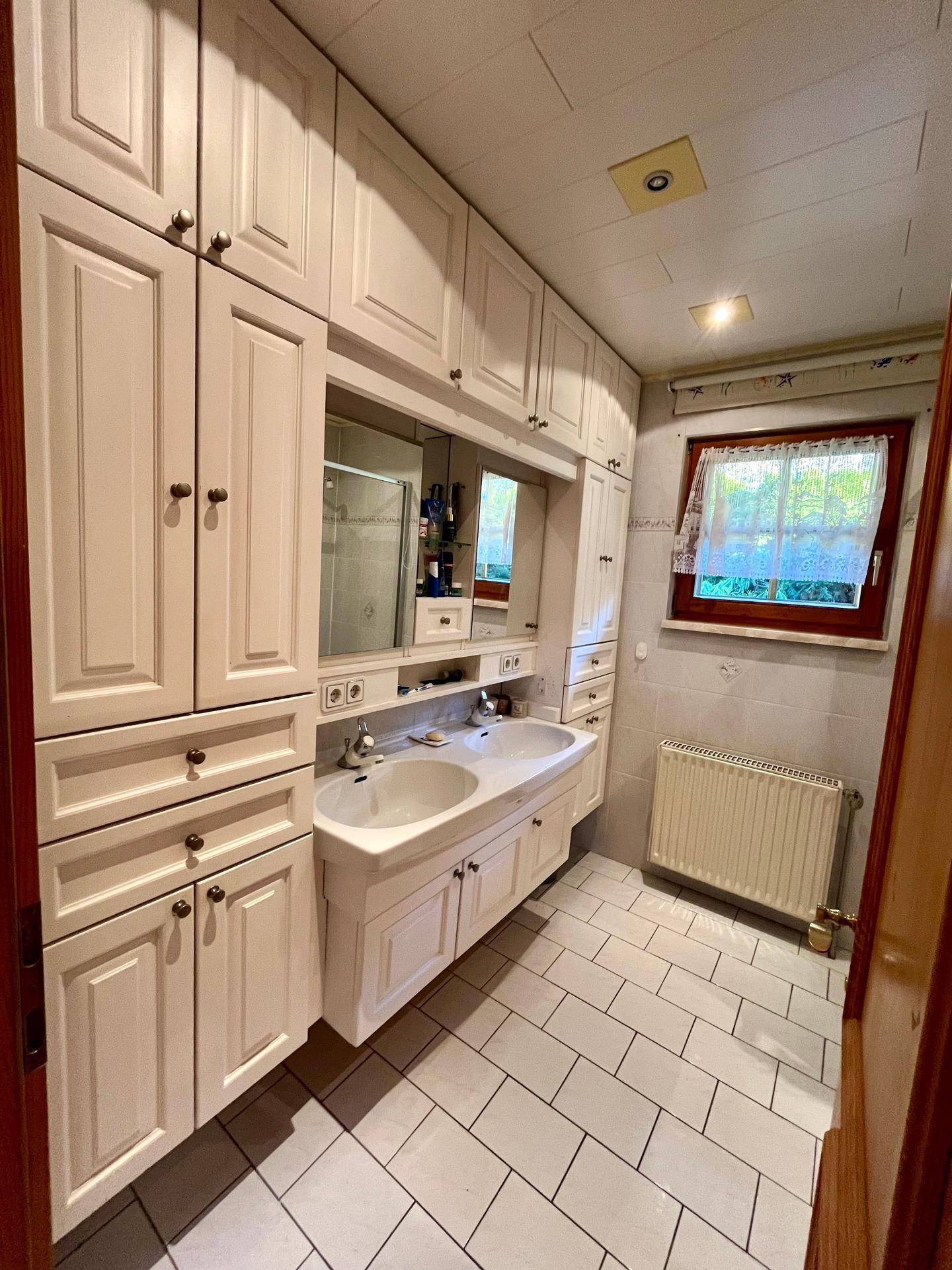 Badezimmer mit Doppelwaschbecken, Spiegelschrank und integrierten Schränken.