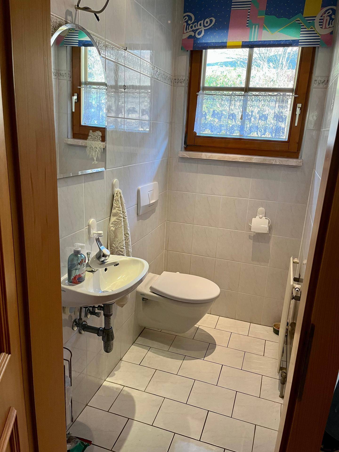 Kleines Gäste-WC mit Fenster, Wand-WC und Handwaschbecken.