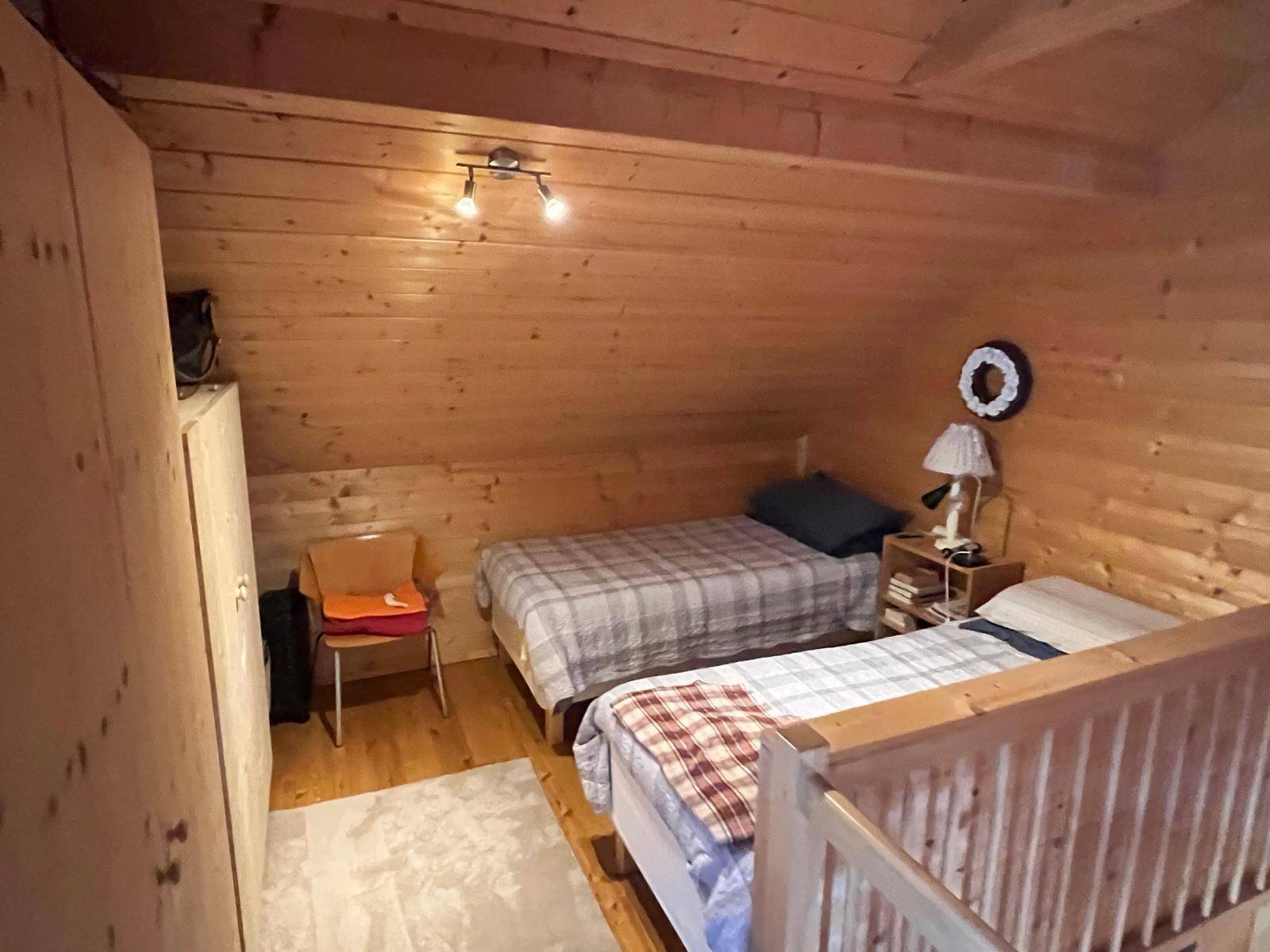 Gemütliches Schlafzimmer im Dachgeschoss mit zwei Einzelbetten und Holzvertäfelung.