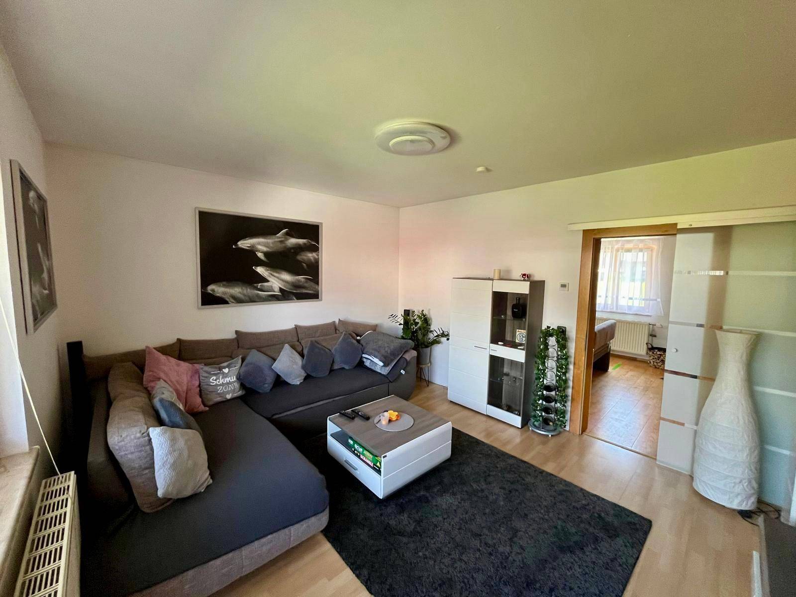 Gemütliches Wohnzimmer mit Ecksofa, Holzboden und modernem Teppich.