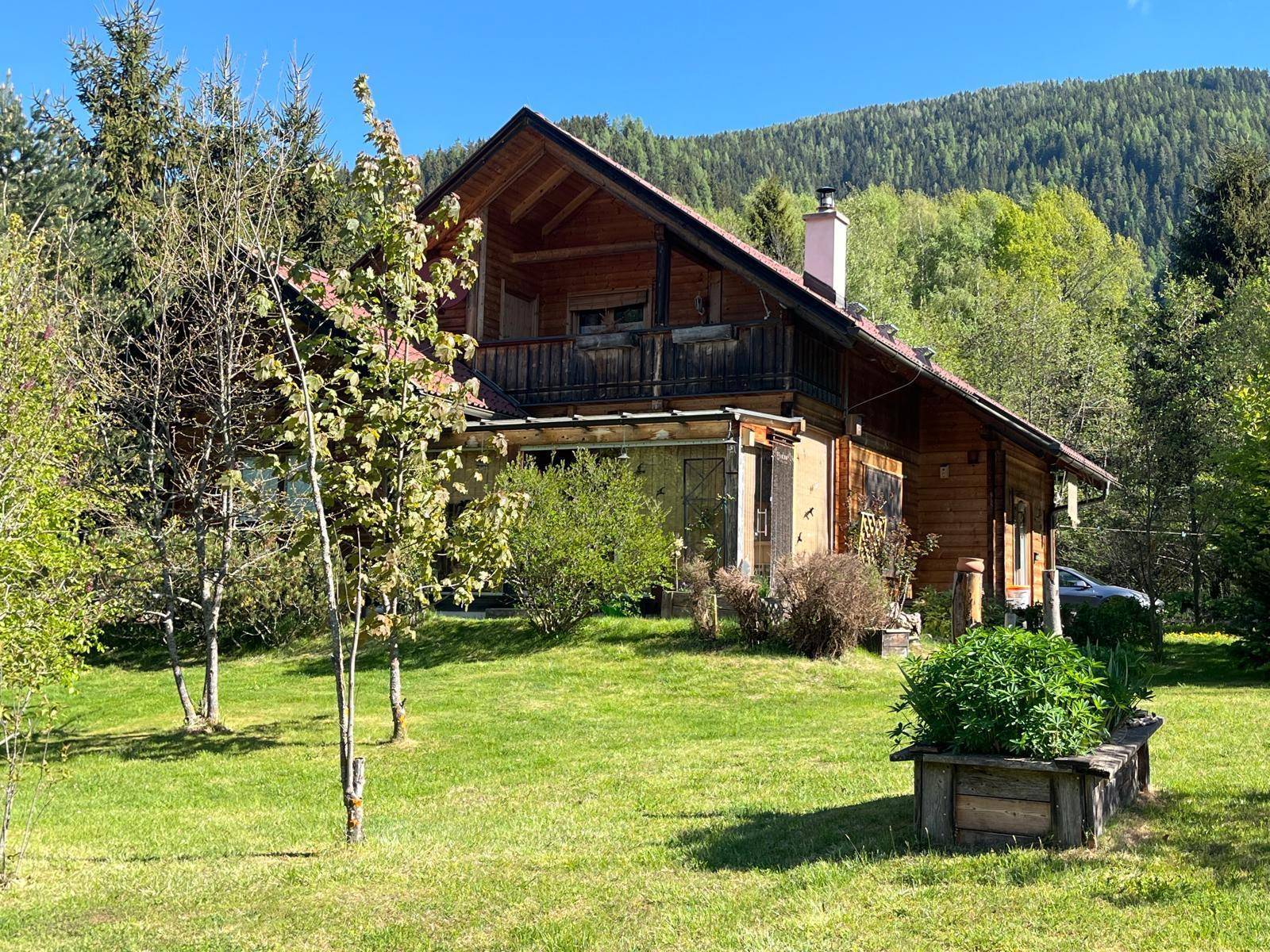 Idyllischer Gartenbereich vor dem Holzhaus mit Blick auf die umliegende Berglandschaft.