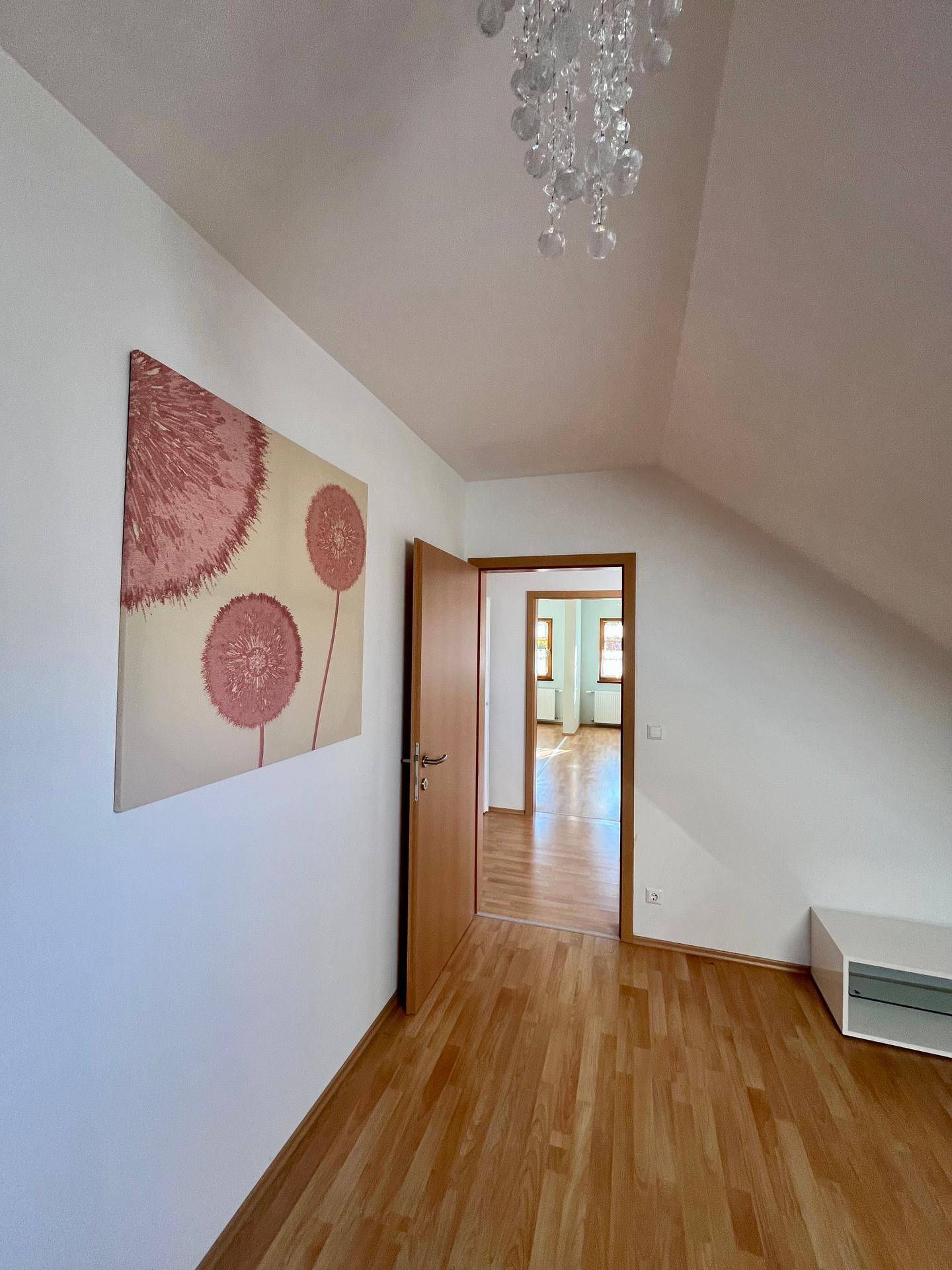 Dachbodenbereich mit Laminatboden, weiß gestrichenen Wänden und moderner Dekoration.