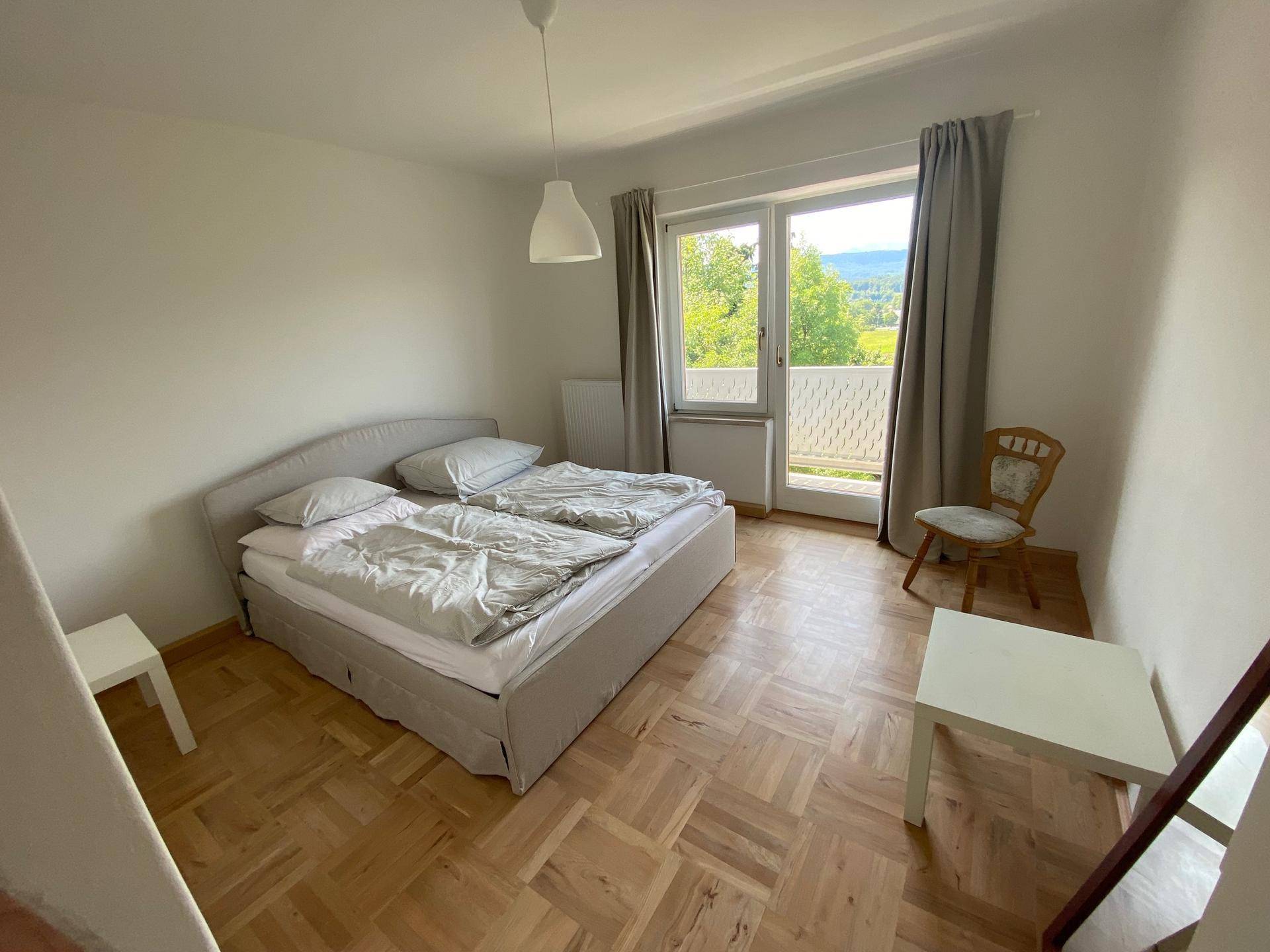 Geräumiges Schlafzimmer mit Doppelbett, Parkettboden und Zugang zu einem Balkon mit schöner Aussicht.