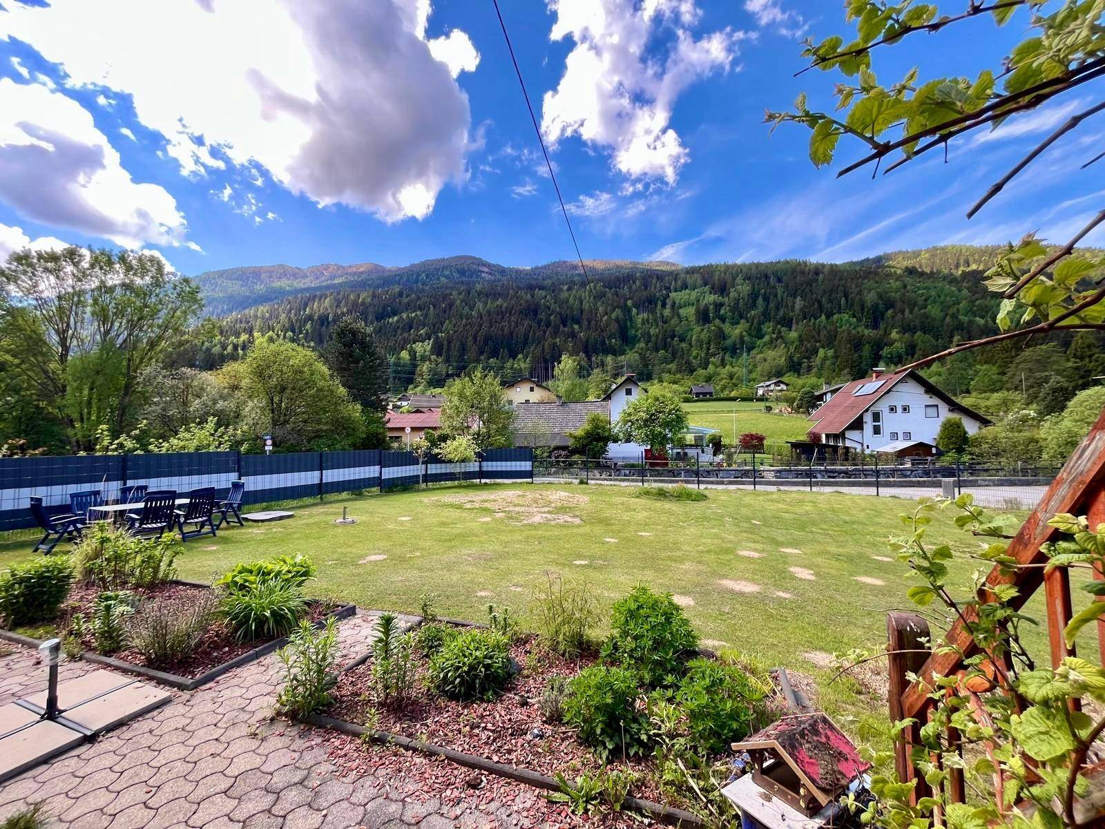 Gepflegter Gartenbereich mit Pflanzen und Blick auf das Haus und die umliegende Berglandschaft.