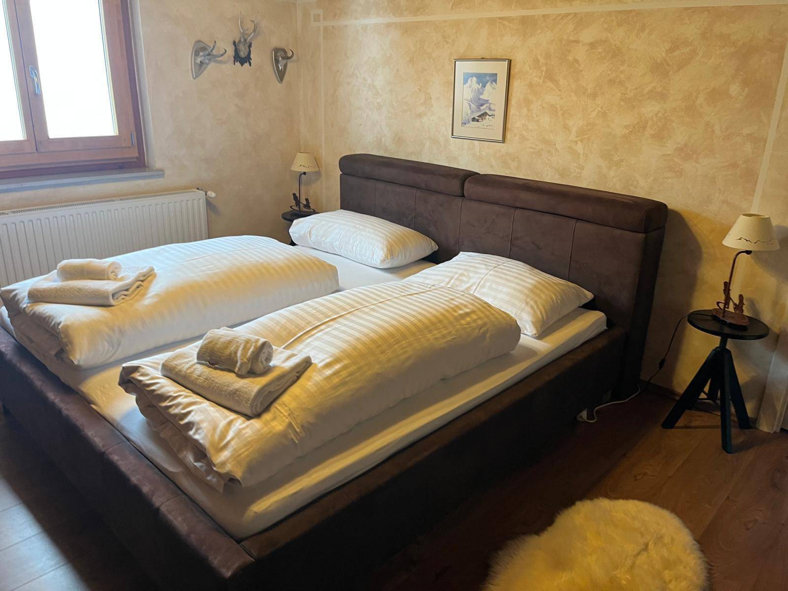 Gemütliches Schlafzimmer mit Doppelbett, Holzboden und traditioneller Wandgestaltung.