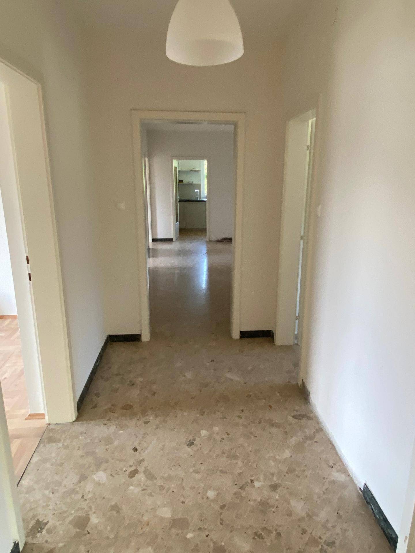 Langer, heller Flur mit Fliesenboden, der zu verschiedenen Räumen der Wohnung führt.