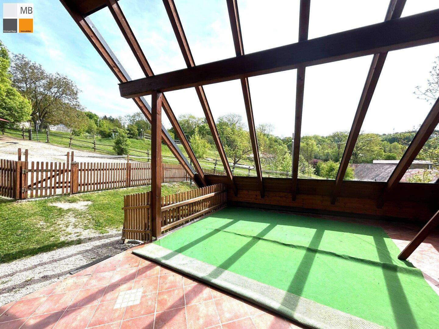 Überdachte Terrasse mit Fliesenboden und weitem Blick auf die umliegende Natur.