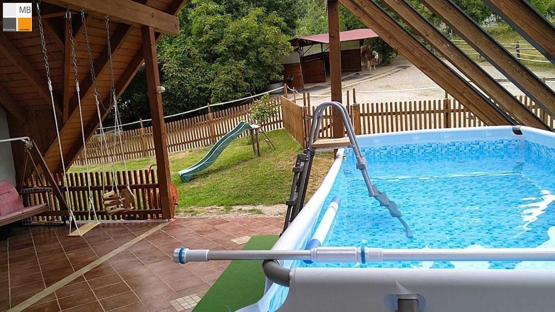 Großer Gartenbereich mit einem Aufstellpool, Rutsche und Schaukel unter einer Holzüberdachung.