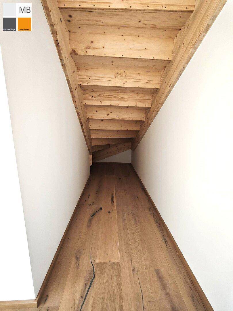Rustikale Holztreppe führt zu einem oberen Stockwerk oder Dachboden, mit Holzbalken sichtbar.
