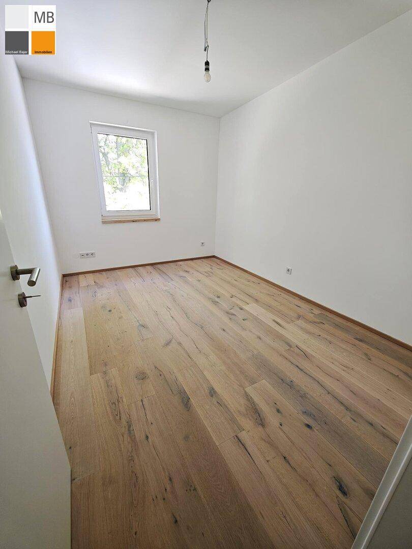 Helles Zimmer mit Holzdielenboden und einem Fenster, das eine angenehme Atmosphäre schafft.