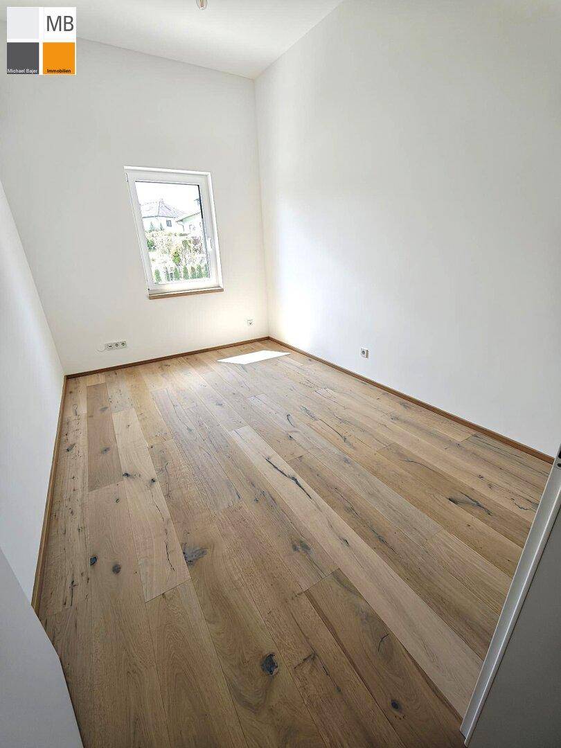 Freundliches Zimmer mit Holzdielenboden und einem Fenster, das den Raum mit Licht füllt.