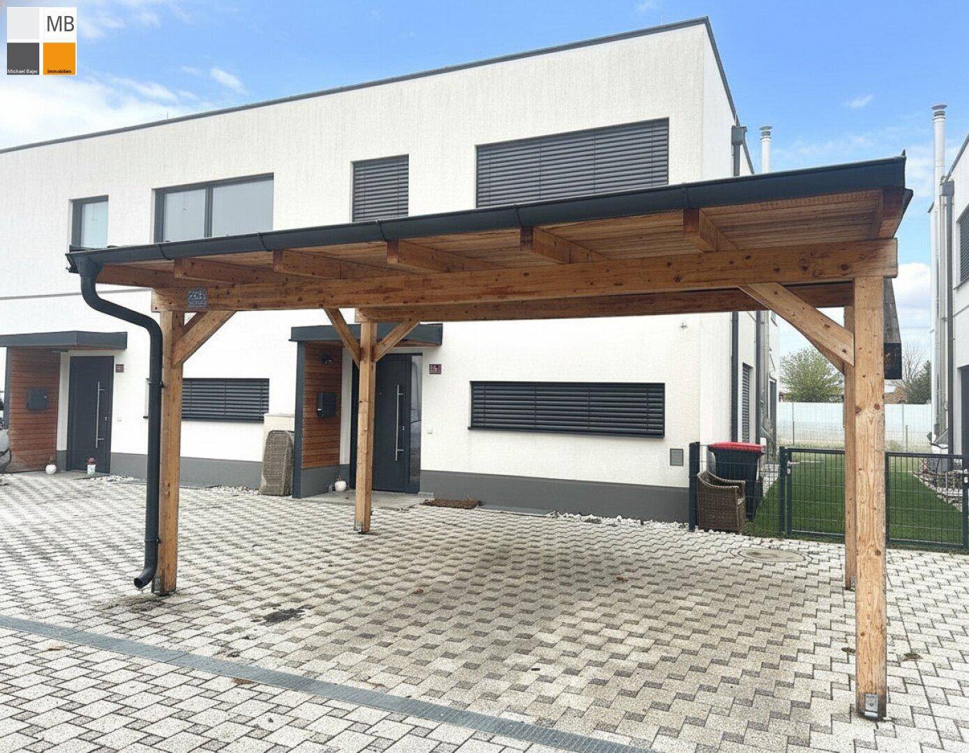 Moderner Holz-Carport vor dem Haus, bietet geschützten Parkplatz für Fahrzeuge.