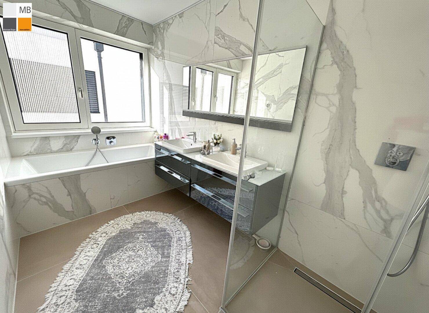 Geräumiges Badezimmer mit Badewanne, Doppelwaschbecken und moderner Dusche, hell und stilvoll.
