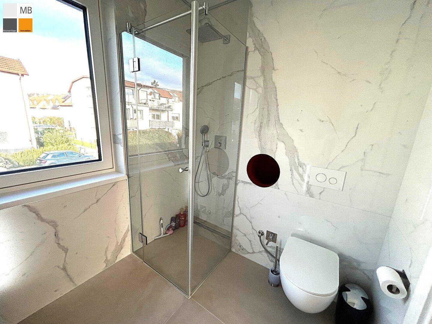 Modernes Badezimmer mit begehbarer Dusche, wandhängendem WC und eleganten Marmorfliesen.